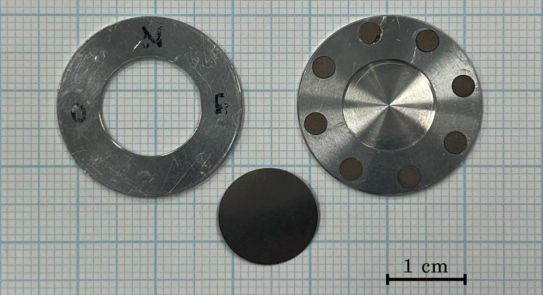 Figure 2: The target coin has a lid (left) with a circular opening, attached to its backside (right) with small magnets. Between the two a single titanium foil is shown.